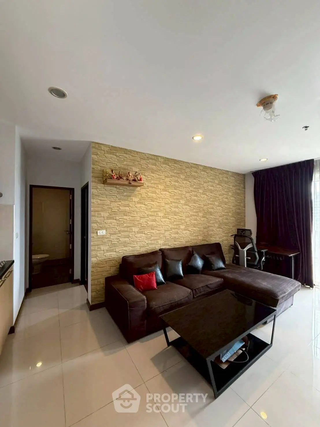 Modern living room with stylish brick accent wall and plush sectional sofa in a cozy apartment.