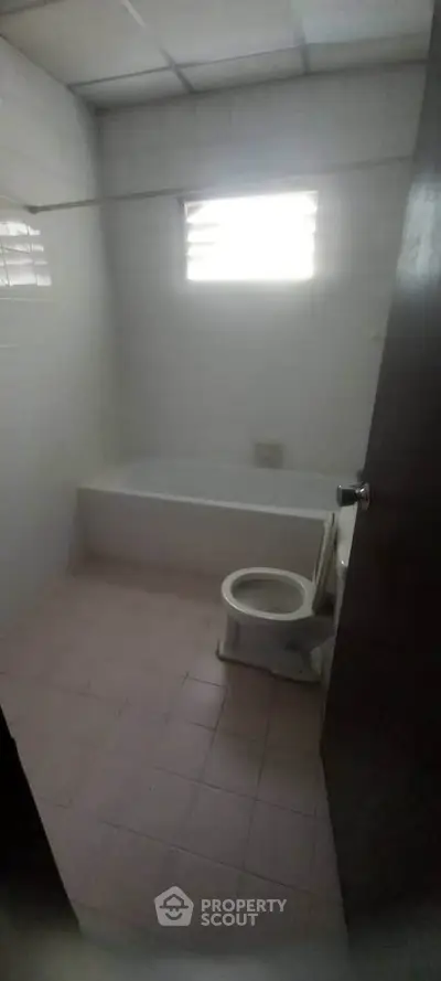 Simple bathroom with bathtub and window, ideal for renovation opportunities.
