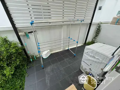 Charming outdoor laundry area with modern drying rack and lush greenery