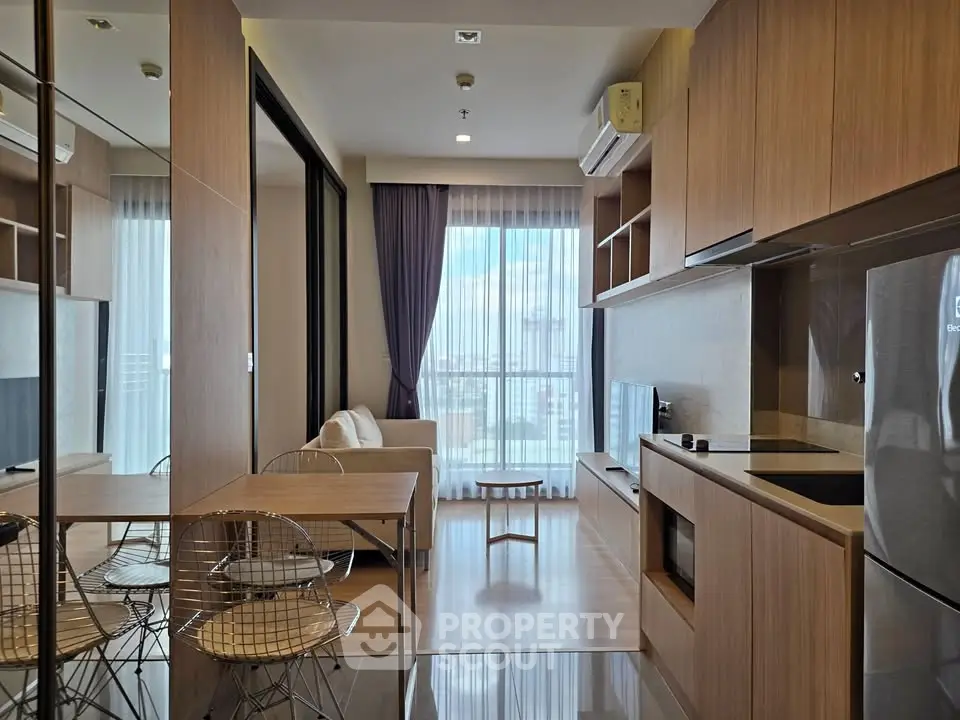 Modern open-layout living room with kitchen, featuring sleek wooden finishes and natural light.