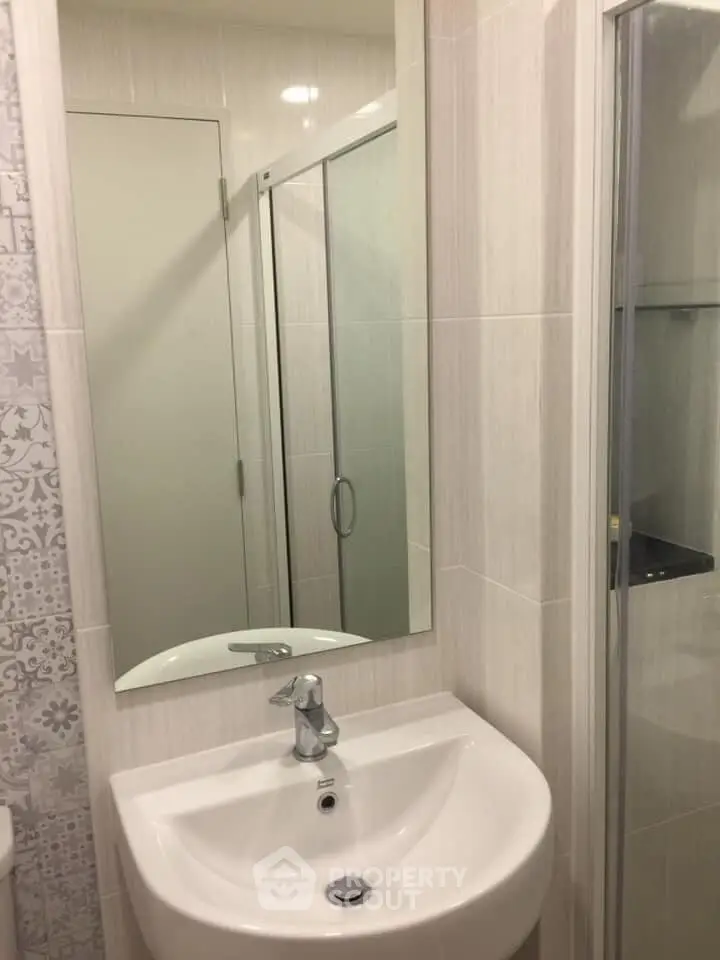 Modern bathroom with sleek sink and glass shower enclosure in stylish apartment.