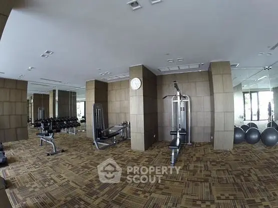 Spacious modern gym with state-of-the-art equipment and stylish decor in luxury residential building.