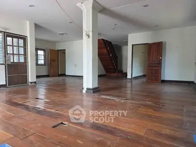 Spacious interior with wooden flooring and staircase, ideal for renovation or customization.