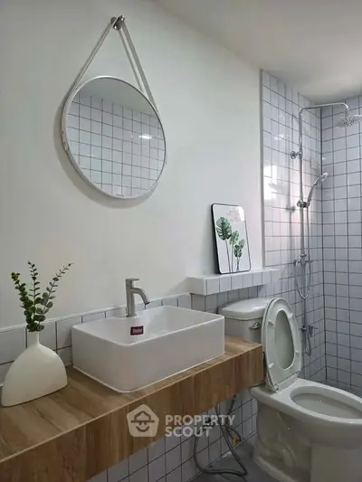 Modern bathroom with stylish sink, round mirror, and elegant shower area.