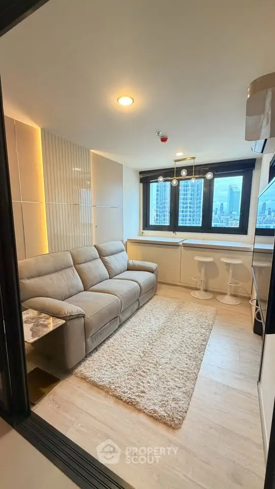 Modern living room with city view, cozy sofa, and stylish decor in high-rise apartment.