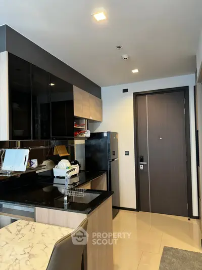 Modern kitchen with sleek black cabinets and marble countertop in stylish apartment.