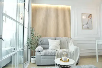 Elegant living room with modern decor, featuring a cozy gray sofa, stylish wall paneling, and chic artwork.