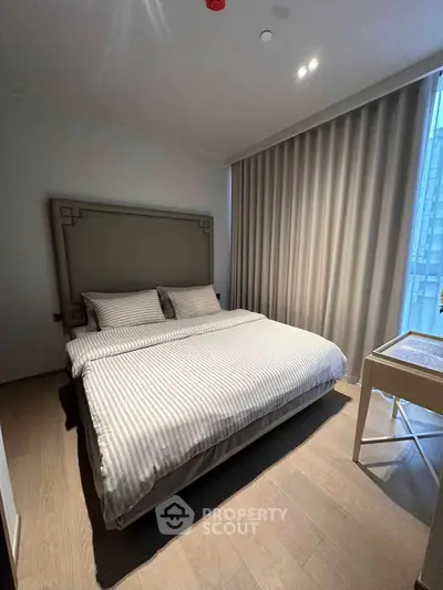 Modern bedroom with stylish decor and large window, featuring a comfortable bed and elegant curtains.