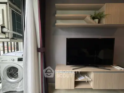 Modern living room with TV, shelves, and washing machine on balcony.