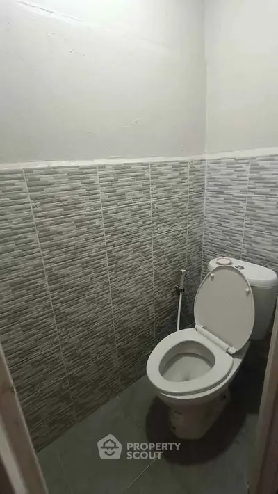 Compact bathroom with modern tiled walls and standard toilet fixture.