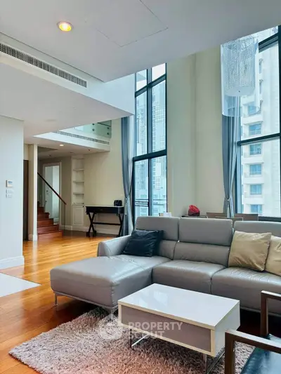 Luxurious modern living room with high ceilings and large windows offering stunning city views.