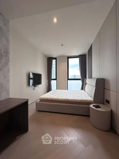 Modern bedroom with large windows and minimalist decor, featuring a mounted TV and stylish furniture.