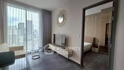 Modern living room with city view, sleek furniture, and natural light in a high-rise apartment.