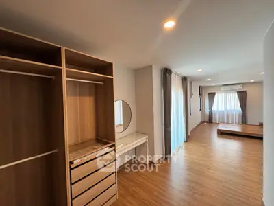 Spacious bedroom with wooden flooring and built-in wardrobe, featuring natural light and modern design.
