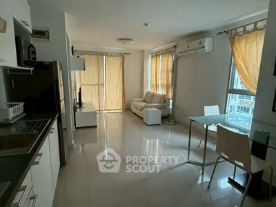 Modern living room with sleek kitchen and natural light in a stylish apartment.