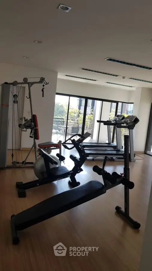 Modern gym with exercise equipment and large windows for natural light.