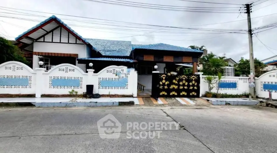 Charming single-story home with blue roof and decorative fence in a serene neighborhood.