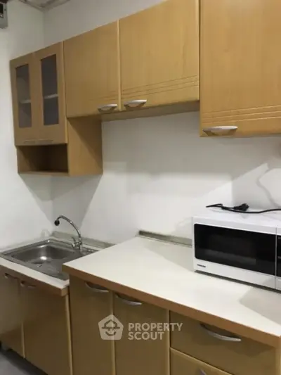 Compact kitchen with wooden cabinets and modern appliances