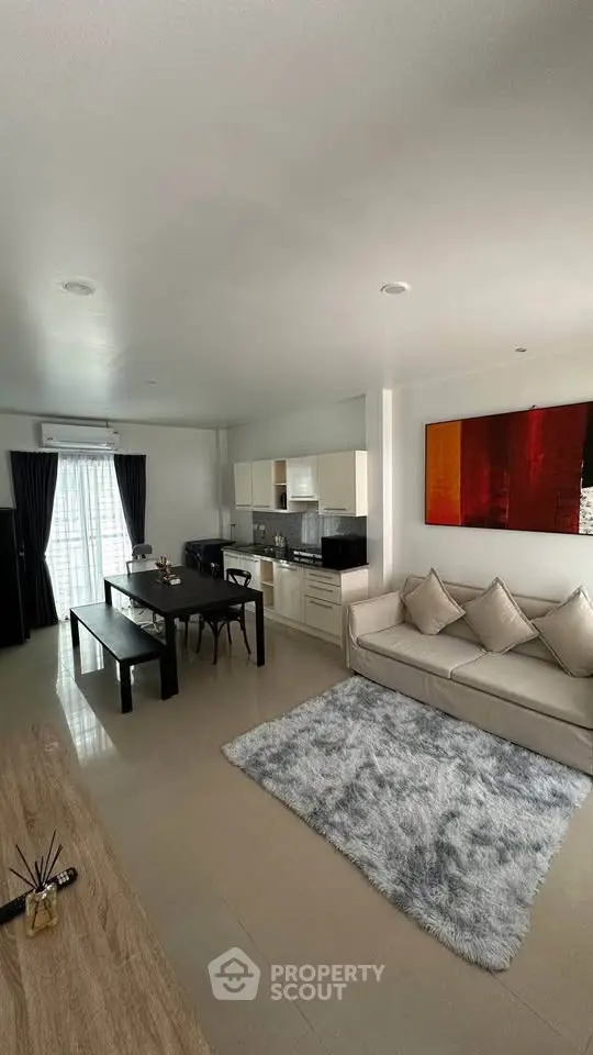Spacious modern living room with open kitchen, stylish decor, and natural light.