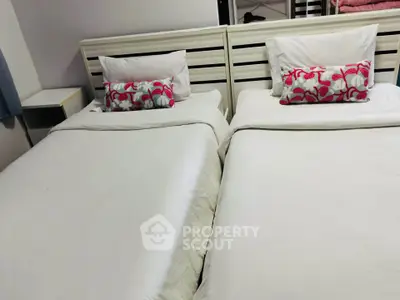 Cozy bedroom with twin beds and stylish pillows in modern apartment.