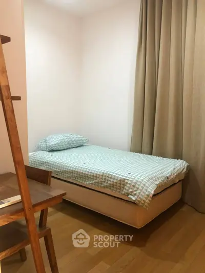 Cozy minimalist bedroom with single bed and wooden furniture, perfect for a small space.