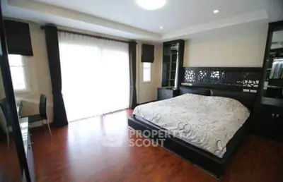 Spacious bedroom with elegant decor and large windows for natural light.