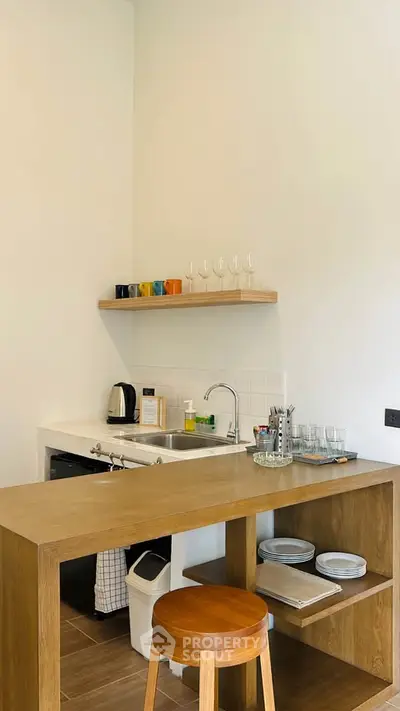 Charming kitchen with modern wooden counter and open shelving, perfect for cozy living.