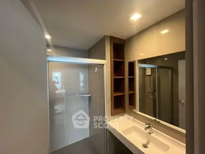 Modern bathroom with sleek design, featuring a spacious shower and elegant vanity mirror.
