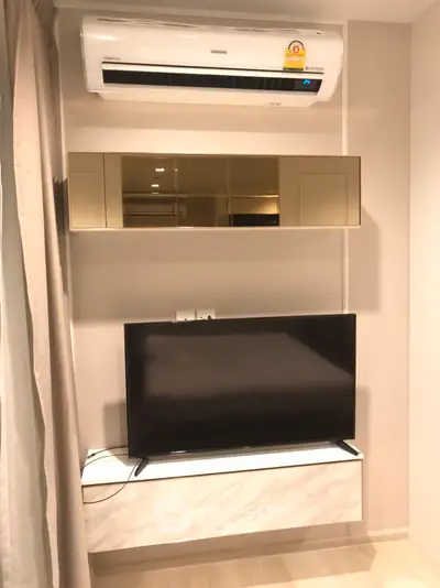 Modern living room with sleek TV setup and air conditioning unit