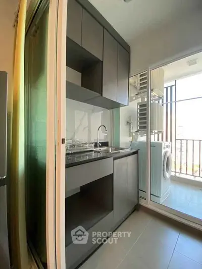 Modern compact kitchen with sleek cabinetry and balcony view featuring a washing machine.