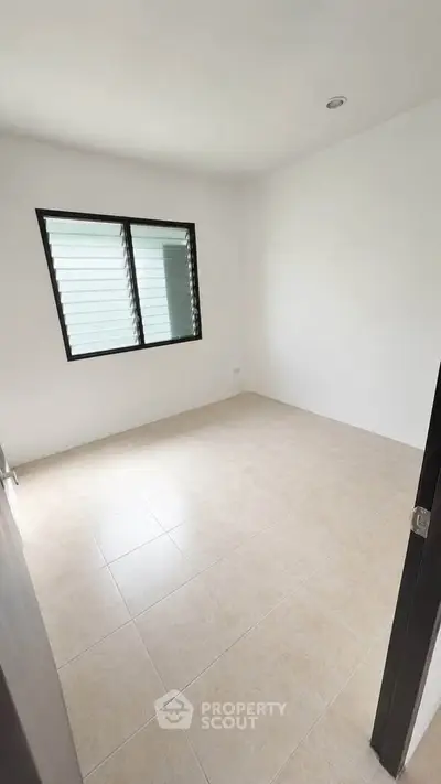 Spacious empty room with tiled floor and large window, perfect for customization.