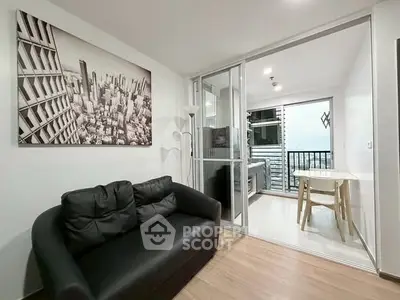 Modern living room with black sofa and cityscape artwork, leading to a balcony with a view.