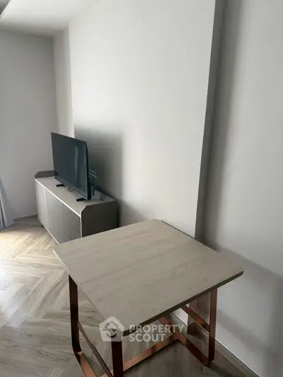 Modern living room with sleek TV stand and stylish wooden table on herringbone floor.