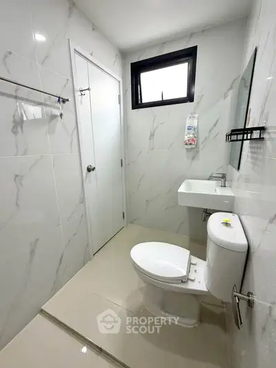 Modern bathroom with sleek white fixtures and marble tile walls