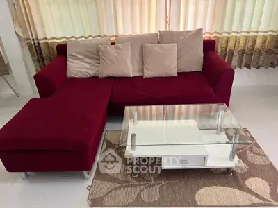 Stylish living room with red sofa and glass coffee table, perfect for modern interiors.