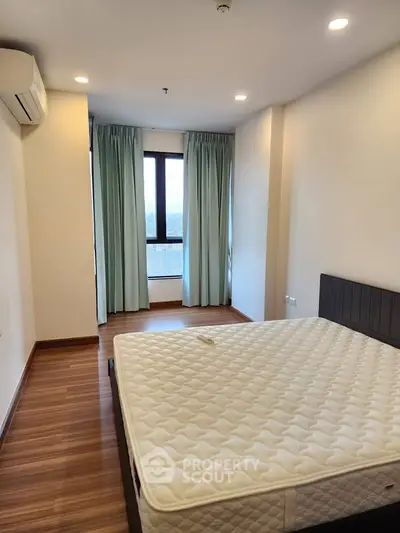 Spacious bedroom with large window and modern design in a high-rise apartment.