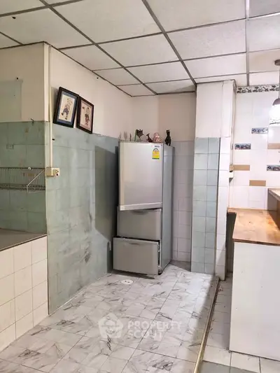 Spacious kitchen with tiled flooring and modern fridge, ideal for culinary enthusiasts.