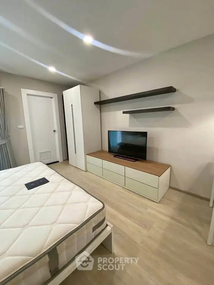 Modern bedroom with sleek furniture and mounted TV, showcasing minimalist design and ample storage.
