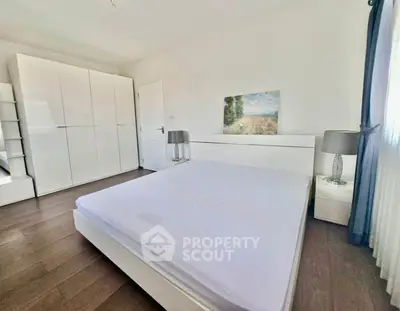 Spacious modern bedroom with sleek white furniture and natural light