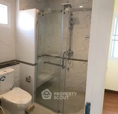 Modern bathroom with glass shower enclosure and elegant marble tiles.
