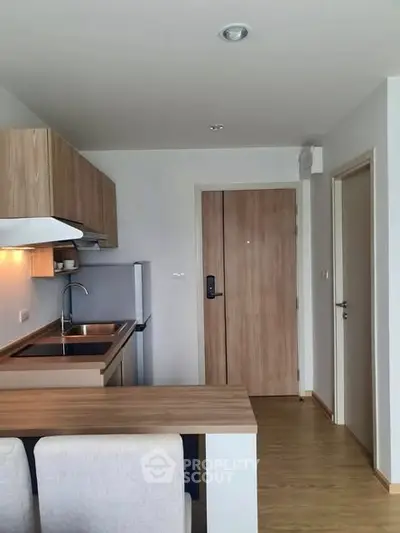 Modern compact kitchen with wooden cabinets and sleek design in a cozy apartment.