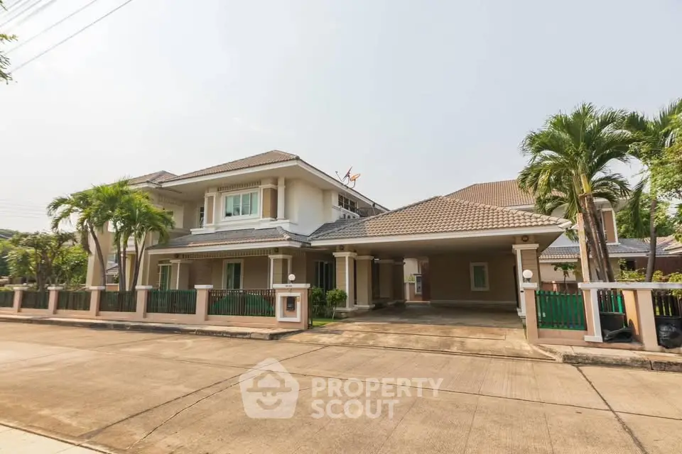 Elegant two-story house with palm trees and spacious driveway in a serene neighborhood.
