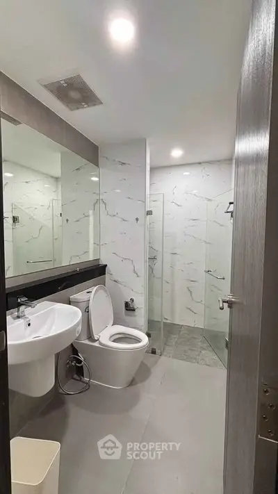 Modern bathroom with sleek fixtures and glass shower enclosure in a contemporary apartment.