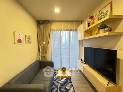 Modern living room with stylish decor, large TV, and city view through sheer curtains.