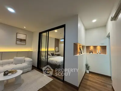 Modern interior with cozy living room and stylish bedroom separated by glass wall.