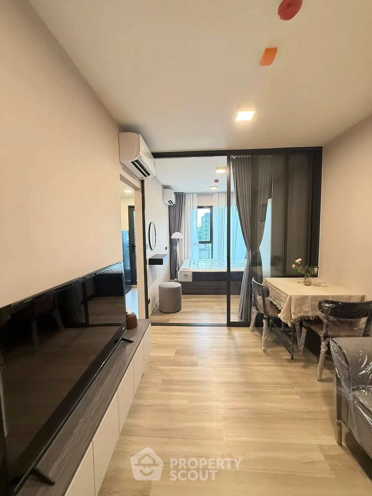 Modern apartment interior with open living and dining area, featuring a view into the bedroom.