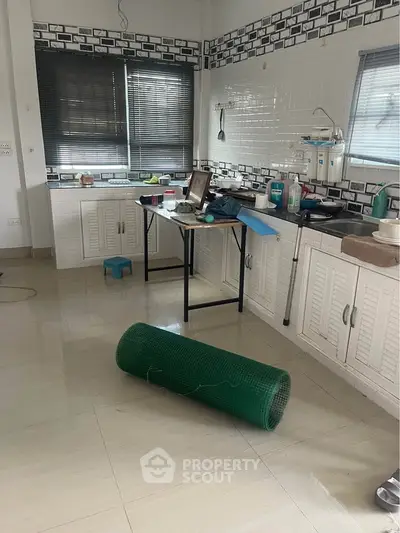 Spacious kitchen with modern design and ample natural light, featuring sleek cabinetry and tiled backsplash.
