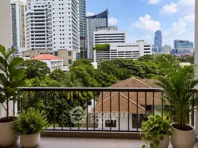 Stunning city view from a modern balcony with lush greenery and urban skyline.