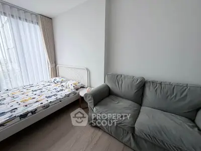Cozy bedroom with a comfortable bed and stylish sofa, featuring large windows for natural light.