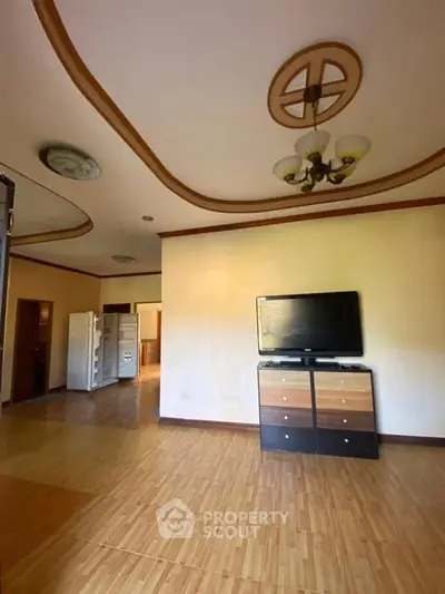 Spacious living room with modern TV setup and elegant ceiling design